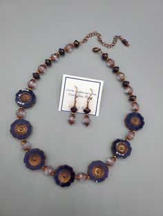 This necklace and earring set is very beautiful and one of my favorites of all time.  All beads used are glass and manufactured in the Czech Republic.  The hibiscus flowers are purple silk with an antique copper wash.  Setting off those flowers and adding the sparkle, are table cut crystal spiral faceted beads that have a purple copper effect applied.  Pretty purple and copper "Saturn" beads are the perfect touch to finish out the beauty of this necklace.  I love Czech glass beads because of their quality and precision. Necklace length is 17" and a 3" extender antique copper chain is attached so you can adjust necklace to your neckline.  Photos show short and extended lengths.  Earrings are 1 and 5/8" long and are finished with 100% Copper hook wires. Nickel-free Czech Glass Flower Jewelry, Gold Czech Glass Flower Jewelry, Gold Czech Glass Flower Shaped Jewelry, Gift Jewelry With Flower Charm And Czech Glass, Gift Jewelry With Flower Charm In Czech Glass, Dark Red Jewelry, Purple And Copper, Red Jewelry Set, Purple Flower Necklace