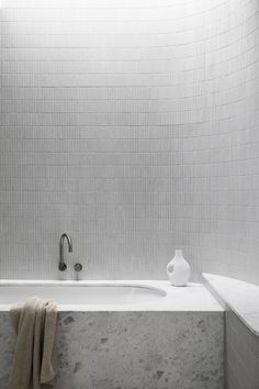 a white bath tub sitting under a window next to a towel on a counter top