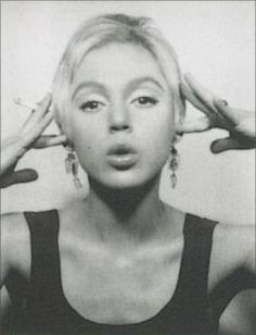 a black and white photo of a woman holding her hands up to her head with one hand