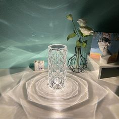 a glass vase sitting on top of a table next to a white flower in a vase