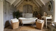 an old fashioned bathtub in a rustic bathroom with wood flooring and stone walls