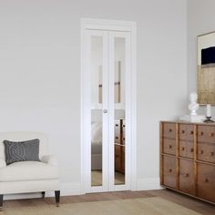 a white chair sitting in front of a mirror next to a dresser with drawers on it