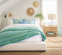 a bed in a bedroom with white walls and carpeted flooring next to a window