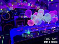 balloons are lit up on the table for a party with glow in the dark decorations