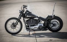 a black motorcycle parked on top of a parking lot next to a sidewalk with no people