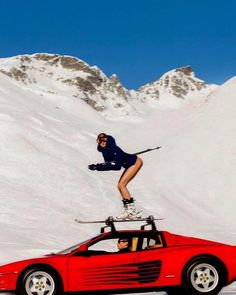 a person on skis jumping over a red sports car