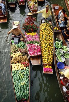 several boats filled with lots of different types of fruit and vegetables sitting in the water