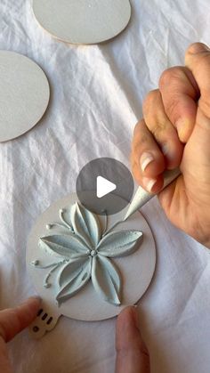 a person is using a knife to cut out paper flowers on a white table cloth