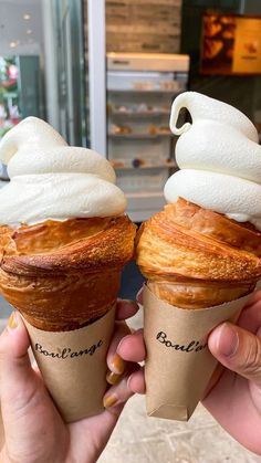 two ice cream cones with whipped cream on top are being held in front of the camera