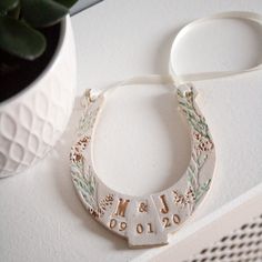 a close up of a necklace on a table near a potted plant