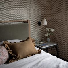 a bedroom with a bed, nightstand and lamp on top of the headboard is shown