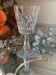 two crystal goblets sitting on top of a glass table next to an orange flower