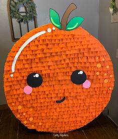 an orange made out of construction paper sitting on top of a wooden floor