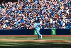 a baseball player throwing a ball on top of a field in front of a crowd