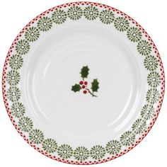 a white and green plate with holly designs on the rim, holding two red berries