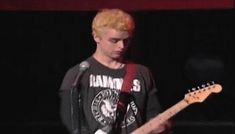 a young man with blonde hair playing an electric guitar