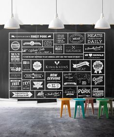 a chalkboard wall with different types of food on it and three stools in front of it