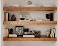 three wooden shelves with books and vases on them