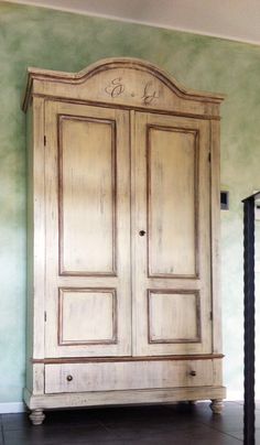 an old wooden armoire in a room with green paint on the walls and floor