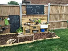 an outdoor kitchen made out of pallets in the grass with chalkboard on the wall