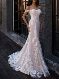 a woman in a white wedding dress standing on a wooden floor next to a building