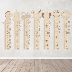 a wooden growth chart with animals on it in front of a white wall and wood floor