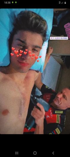 a shirtless man with red hearts on his chest holding a cell phone in front of him