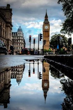 the big ben clock tower towering over the city of london, reflected in a puddle