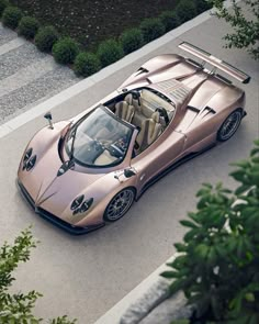 an overhead view of a pink sports car parked on the side of a road next to some bushes