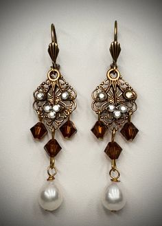 Fresh water pearls, Smokey topaz Swarovski crystal beads and a lovely crystal leaf design make up the design of these lovely handcrafted brass with brass plated earrings. These filigree chandelier earrings have three crystal brown beads, multi color clear crystal stones on a leaf that moves with a freshwater pearl drop. They are about 2 1/2" long-see the photo (the filler photo is the same style but a different color than this listing). Sporting a lever back earring wire  with a decorative front Elegant Brown Chandelier Earrings, Elegant Brown Brass Earrings, Elegant Bronze Brass Chandelier Earrings, Victorian Dangle Chandelier Earrings In Brass, Victorian Brass Dangle Chandelier Earrings, Elegant Copper Chandelier Earrings, Elegant Antique Gold Brass Chandelier Earrings, Vintage Gold Chandelier Earrings With Pearl Drop, Elegant Brown Earrings With Dangling Beads