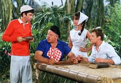 three men and one woman are sitting at a picnic table in front of palm trees