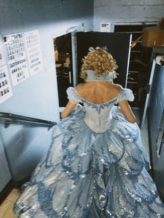 a woman in a blue and silver dress is looking down at the refrigerator freezer