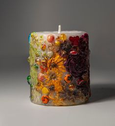 a candle that has been made out of glass beads and flowers on the inside of it