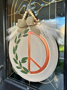 a peace sign is hanging on the glass front door with feathers and beads around it