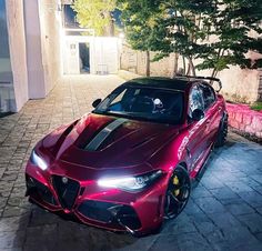 a red sports car parked in front of a building at night with its lights on