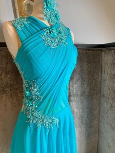 a blue dress with beading on the neckline and shoulders is displayed in front of a mannequin