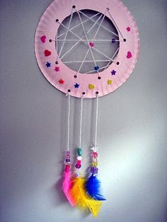 a pink dream catcher hanging from the side of a wall with hearts and stars on it