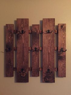 a wooden wall mounted to the side of a white wall with hooks on each end