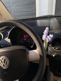 the steering wheel and dashboard of a car with a purple flower in it's center