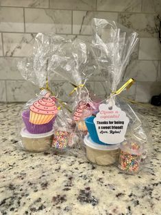 three cupcakes wrapped in plastic bags on a counter