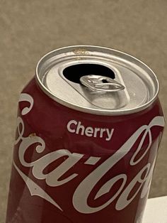 a can of coca - cola sitting on top of a white table next to a sidewalk