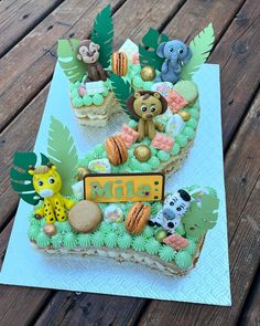 an animal themed birthday cake on top of a wooden table with leaves and animals around it