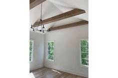 an empty room with three windows and wood beams