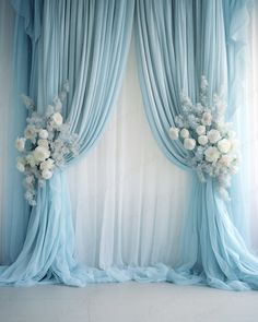 the curtains are open and decorated with flowers in white and light blue colors, as well as sheer drapes