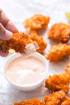 a person dipping sauce on some fried food