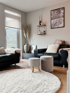 a living room with two black couches and a white rug on the wooden floor