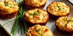 several small muffins are sitting on a tray with green beans and chives