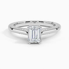 an emerald cut engagement ring with diamonds on the shoulders and sides, set in 18k white gold