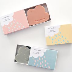 two boxes with soaps in them sitting on a white table next to each other