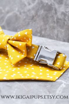 a close up of a yellow bow tie with white stars on it and a silver buckle